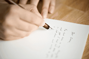 Someone writing a letter with a pen.