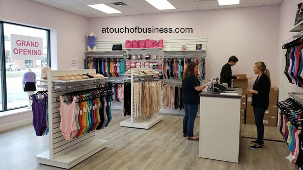 Inside a new retail dancewear store grand opening. Staff stock leotards and tights while managing the checkout counter.