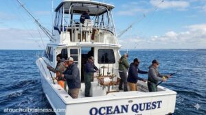 Professional charter fishing boat at sea with clients reeling in fish during a deep-sea excursion.
