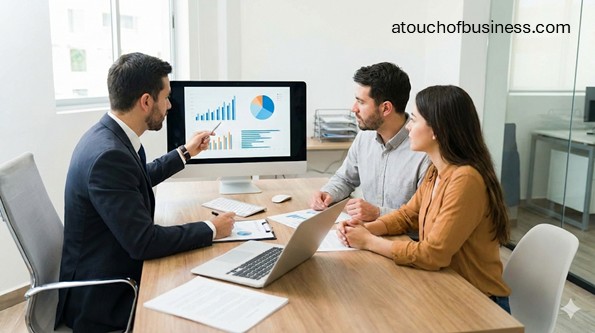 A financial planner discussing investment charts on a screen with a couple during a professional client consultation in an office.
