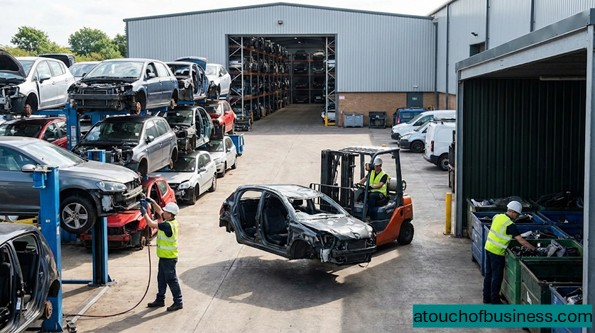 Workers operating a modern auto salvage yard with organized car shells and industrial vehicle dismantling equipment.