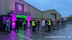 Haunted house business entrance with a line of people, vibrant neon lighting, and staff managing the crowd.