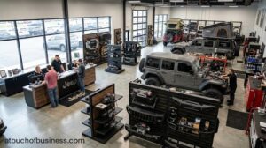 Off-road shop interior showing technicians installing custom accessories on SUVs and customers at the service counter.