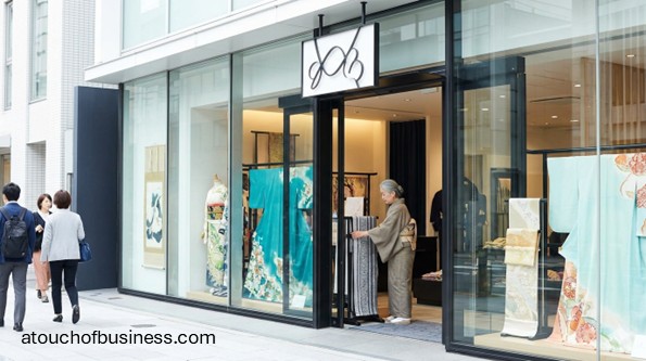 Modern kimono boutique exterior with large glass windows showing colorful silk displays and an older staff member.