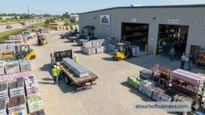 A busy, modern roofing supply company yard, featuring forklifts moving materials, trucks, and unique employees working.