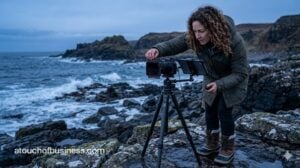 A photographer using specialized filters on a rugged coast at blue hour, representing a photography business.