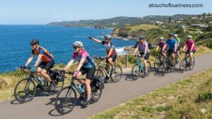 Diverse group riding modern bicycles on a scenic guided coastal tour overlooking the ocean on a clear day.