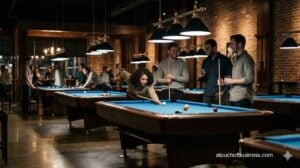 Friends smiling around a blue felt pool table in a dimly lit modern hall.