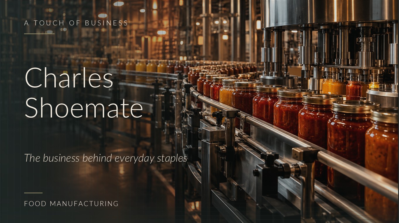 Rows of sauce-filled glass jars passing machinery in an amber-lit packaged-food factory.