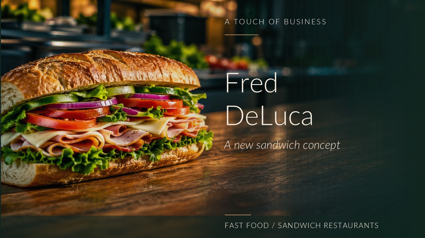 A freshly layered submarine sandwich rests on a wood counter in a warmly lit deli.